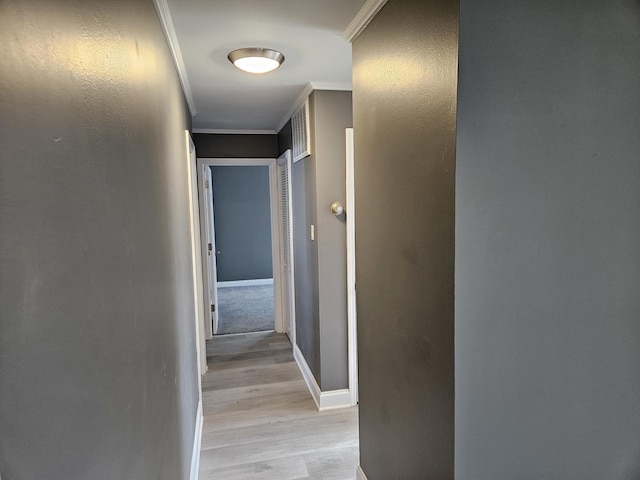 hall with light wood-style flooring, baseboards, and ornamental molding