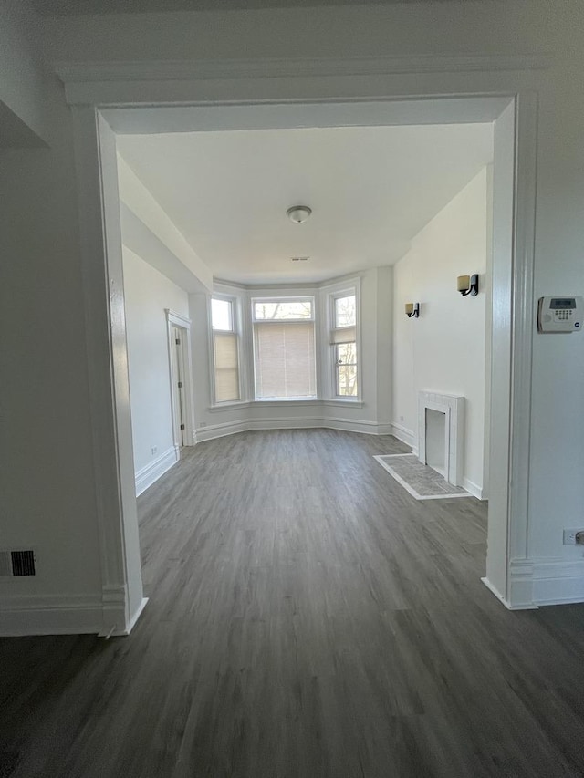 unfurnished living room with visible vents, baseboards, dark wood finished floors, and a fireplace