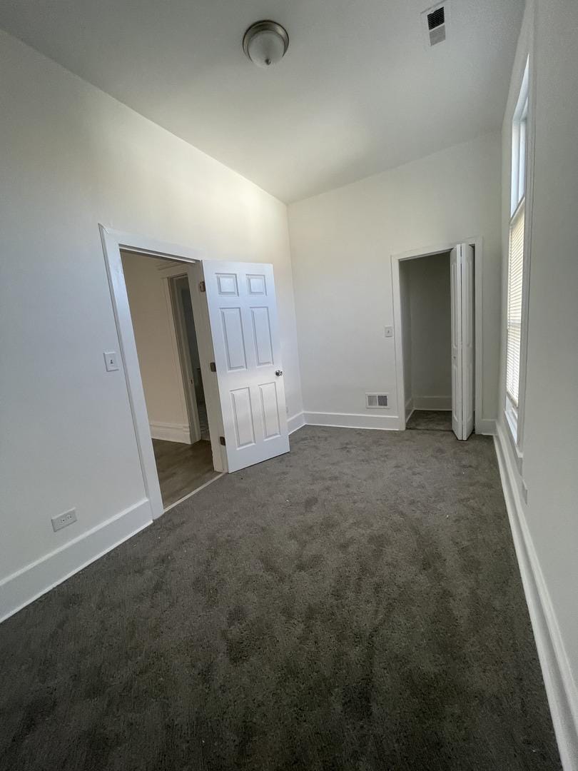 unfurnished bedroom featuring dark colored carpet, visible vents, and baseboards