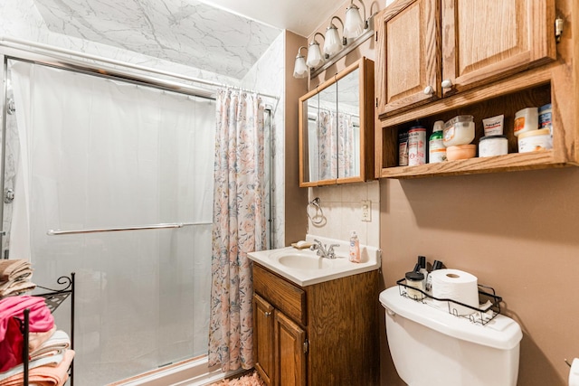 bathroom with toilet, a stall shower, and vanity