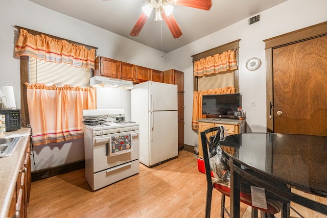 kitchen featuring white appliances, brown cabinetry, light wood-style flooring, ceiling fan, and under cabinet range hood