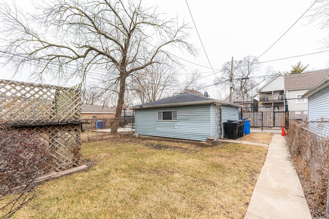 rear view of house with an outdoor structure, a yard, and a fenced backyard