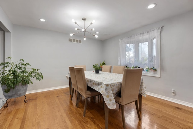 dining area featuring an inviting chandelier, light wood-style floors, visible vents, and baseboards