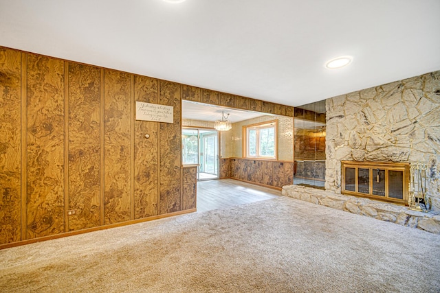 unfurnished living room with a stone fireplace and carpet flooring