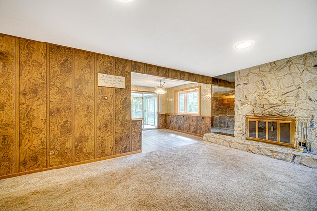 unfurnished living room with a stone fireplace and carpet flooring