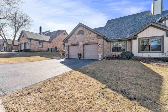 view of front of property featuring aphalt driveway, an attached garage, a front lawn, and brick siding