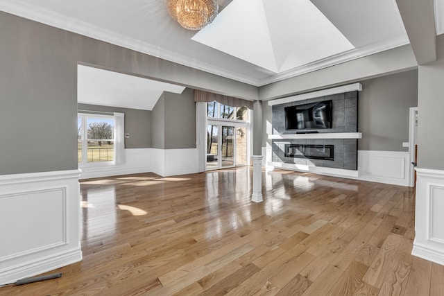 unfurnished living room with a glass covered fireplace, a wainscoted wall, and a wealth of natural light