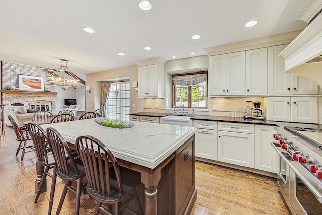 kitchen with premium range hood, double oven range, a kitchen breakfast bar, backsplash, and light wood-style floors