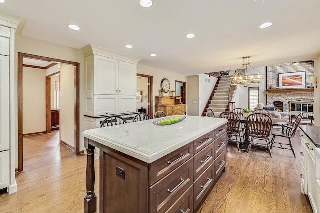 kitchen with light stone countertops, a breakfast bar, recessed lighting, white cabinets, and light wood-type flooring