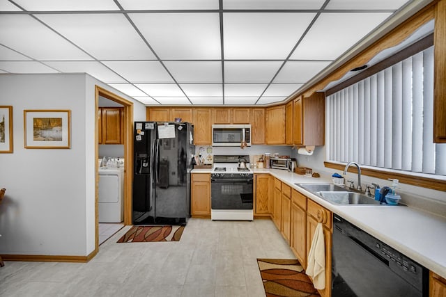 kitchen with black appliances, a sink, washing machine and dryer, light countertops, and a paneled ceiling