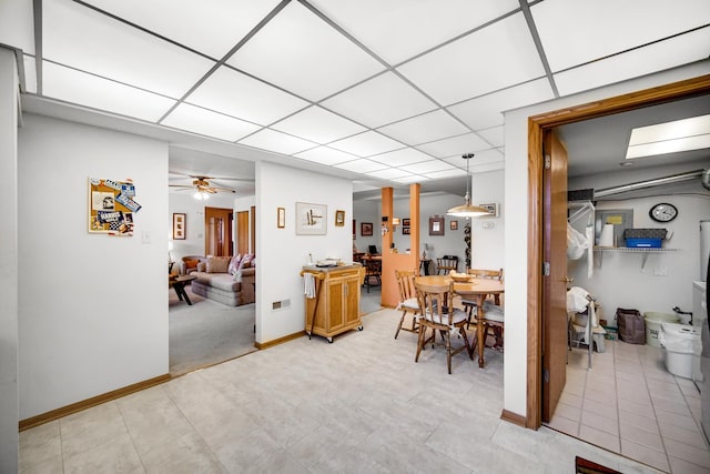 dining room featuring light tile patterned floors, a ceiling fan, a paneled ceiling, and baseboards