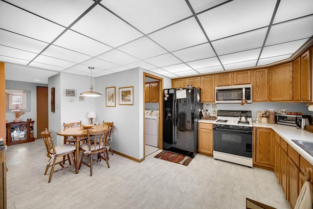 kitchen featuring washer / clothes dryer, light countertops, black fridge with ice dispenser, gas range oven, and stainless steel microwave