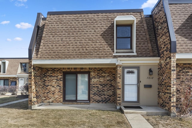 view of front of home featuring brick siding, mansard roof, and a shingled roof