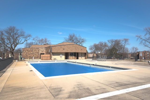 community pool with a patio area and fence