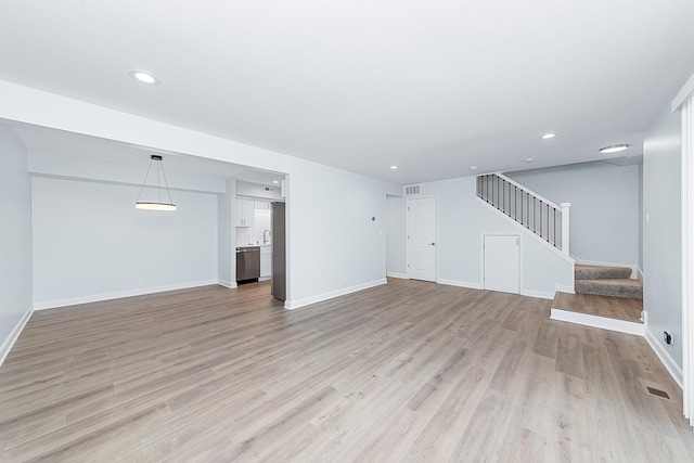 unfurnished living room with visible vents, baseboards, stairs, recessed lighting, and light wood-style flooring