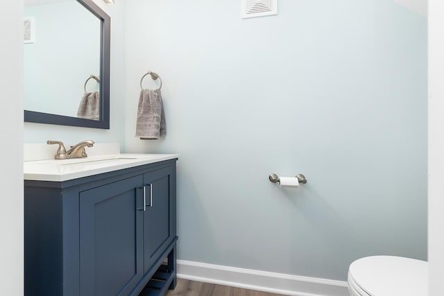 bathroom featuring visible vents, toilet, wood finished floors, baseboards, and vanity