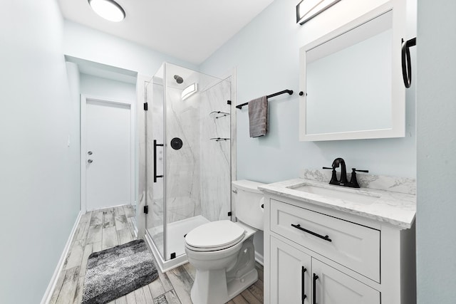 full bath featuring vanity, wood finished floors, baseboards, a marble finish shower, and toilet