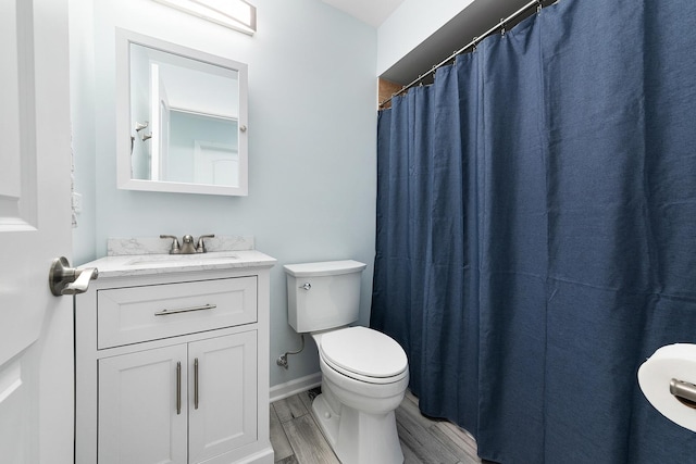 bathroom with toilet, vanity, baseboards, and wood finished floors