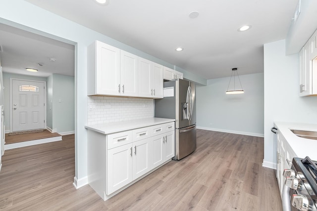 kitchen featuring light wood-type flooring, tasteful backsplash, stainless steel appliances, white cabinets, and light countertops