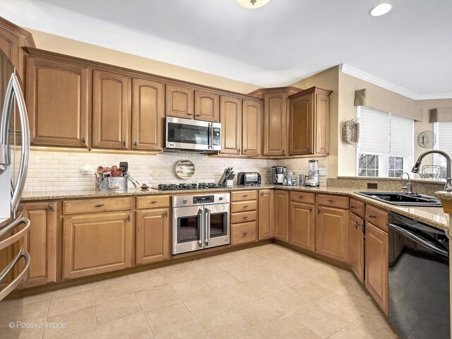 kitchen featuring light stone counters, a sink, stainless steel appliances, and tasteful backsplash