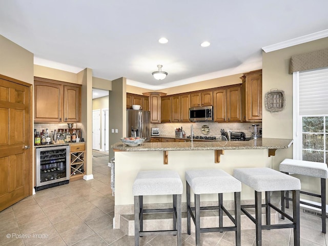 kitchen with backsplash, light stone countertops, beverage cooler, a breakfast bar, and stainless steel appliances