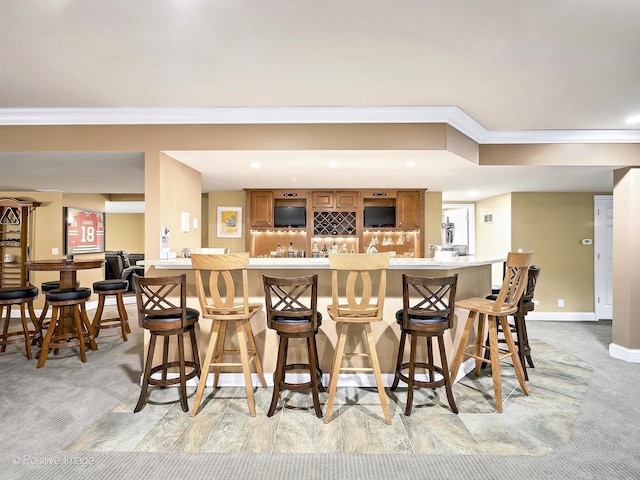 bar with indoor wet bar, light carpet, baseboards, and ornamental molding