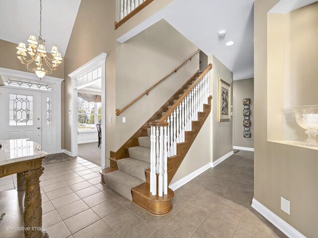 tiled foyer featuring stairs, baseboards, and high vaulted ceiling