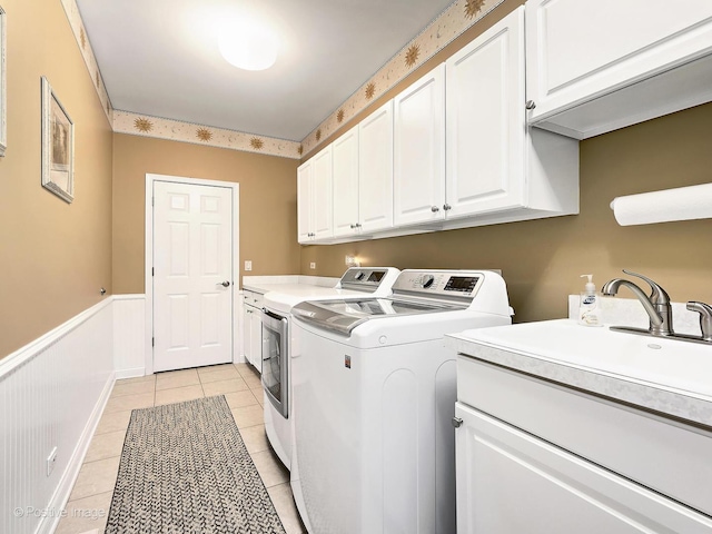 washroom featuring light tile patterned floors, a wainscoted wall, cabinet space, and independent washer and dryer