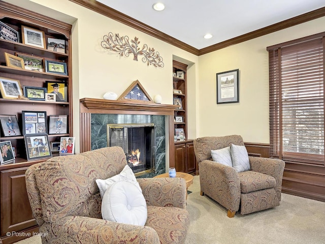 living area with built in shelves, carpet floors, a high end fireplace, ornamental molding, and wainscoting