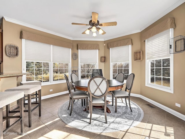 dining space featuring tile patterned flooring, ceiling fan, baseboards, and ornamental molding