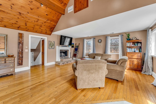 living room featuring light wood-style floors, a fireplace, visible vents, and baseboards