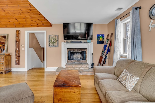 living room featuring visible vents, a fireplace, light wood-type flooring, and baseboards