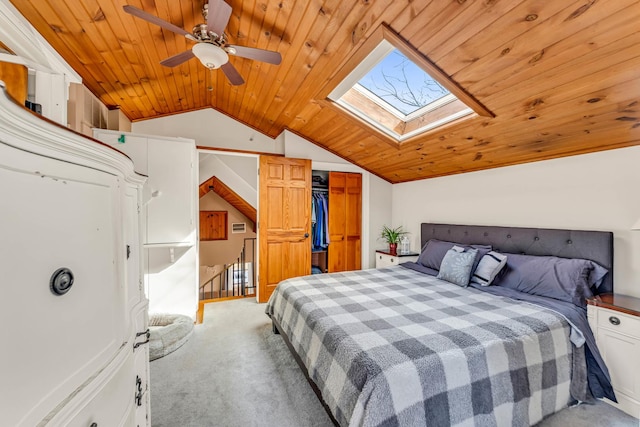 bedroom featuring wood ceiling, vaulted ceiling with skylight, carpet, and a closet