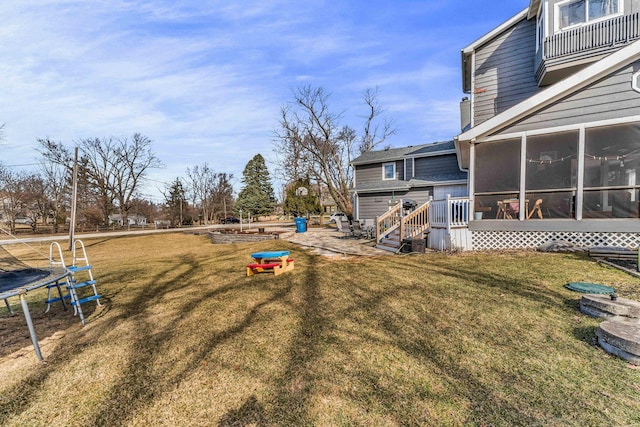 view of yard with a trampoline and a sunroom