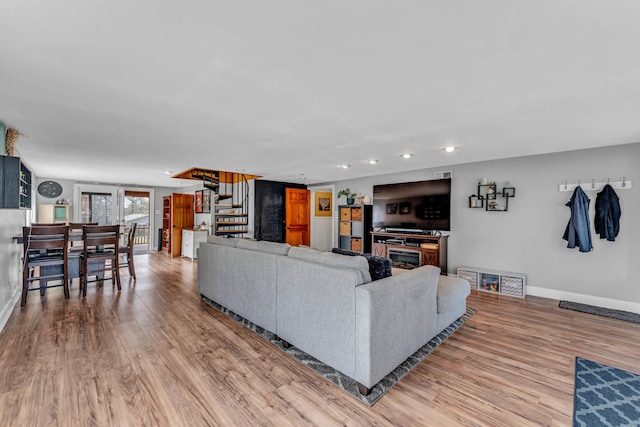 living room featuring stairs, recessed lighting, light wood-style floors, and baseboards