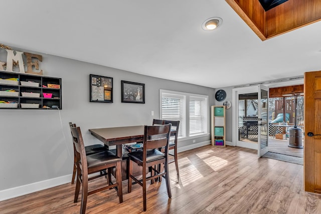 dining space featuring light wood finished floors and baseboards