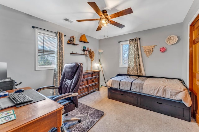 carpeted bedroom featuring visible vents, a baseboard heating unit, and a ceiling fan