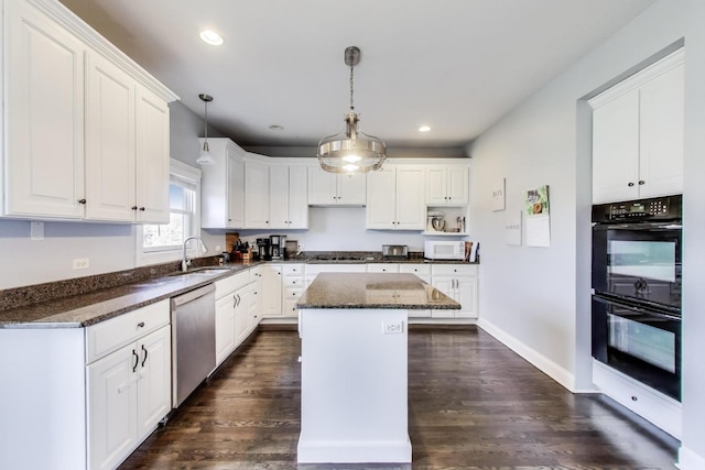 kitchen featuring dark stone countertops, a kitchen island, a sink, white cabinets, and appliances with stainless steel finishes