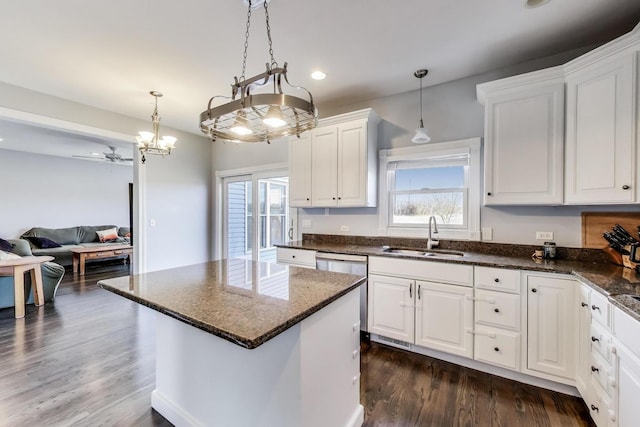 kitchen featuring dark stone countertops, a sink, dark wood-type flooring, white cabinetry, and a center island