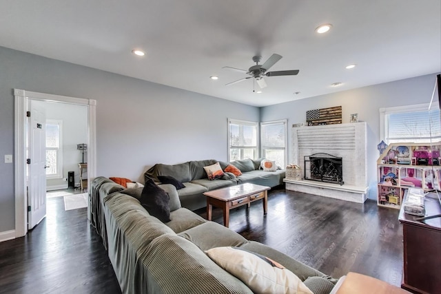 living room featuring a ceiling fan, wood finished floors, baseboards, recessed lighting, and a fireplace with raised hearth