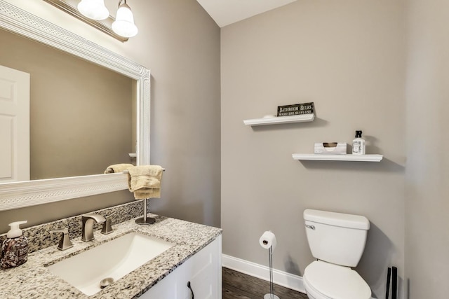 bathroom with baseboards, toilet, wood finished floors, and vanity