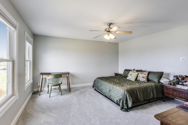 carpeted bedroom featuring multiple windows, a ceiling fan, and baseboards