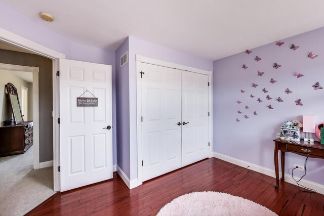 bedroom with visible vents, baseboards, a closet, and wood finished floors