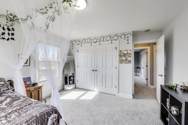 carpeted bedroom with a closet and baseboards