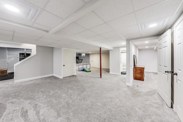 finished below grade area featuring carpet, baseboards, and a drop ceiling