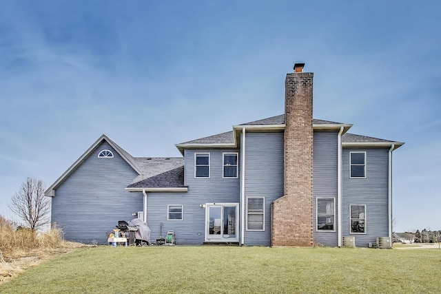 back of property with a lawn, a chimney, and a shingled roof