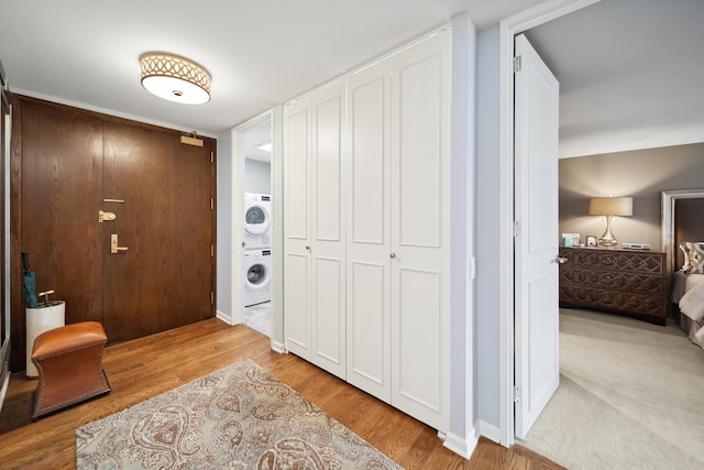 hallway featuring stacked washer and dryer and wood finished floors