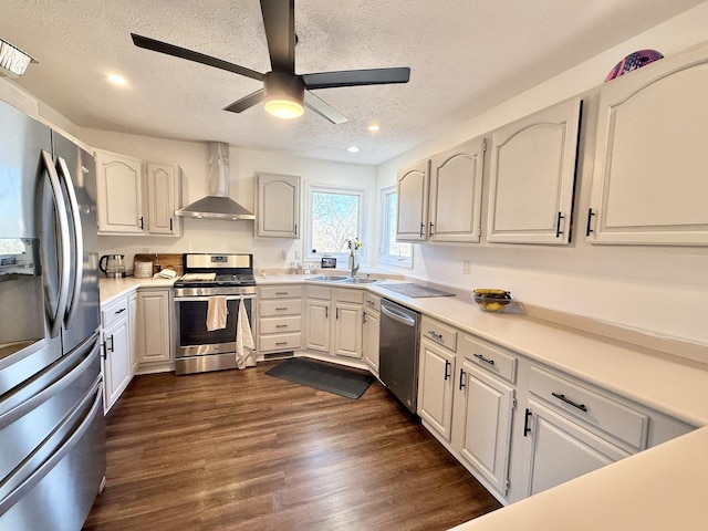 kitchen featuring dark wood-type flooring, light countertops, appliances with stainless steel finishes, wall chimney exhaust hood, and a sink