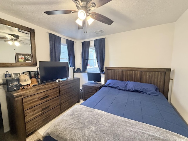 bedroom featuring ceiling fan, visible vents, and a textured ceiling