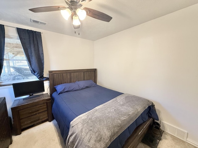 carpeted bedroom featuring baseboards, visible vents, a textured ceiling, and a ceiling fan